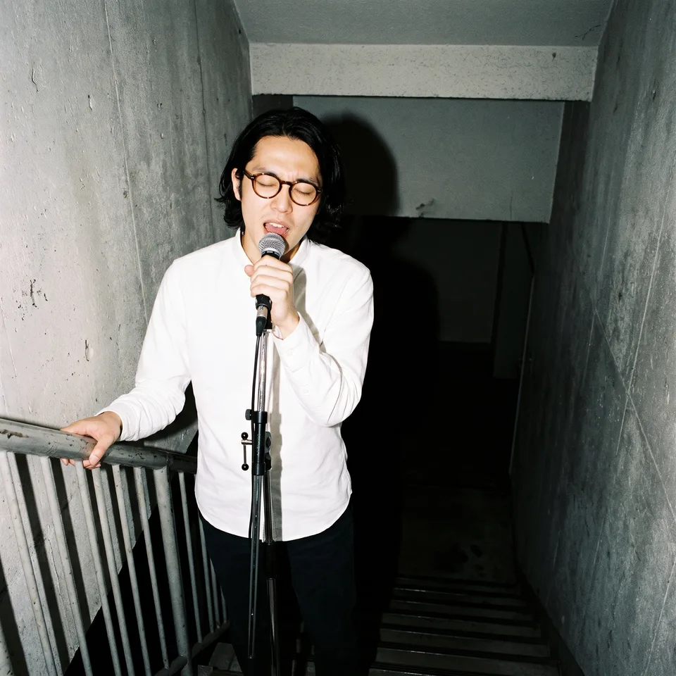 Benny singing into a microphone in the stairwell.