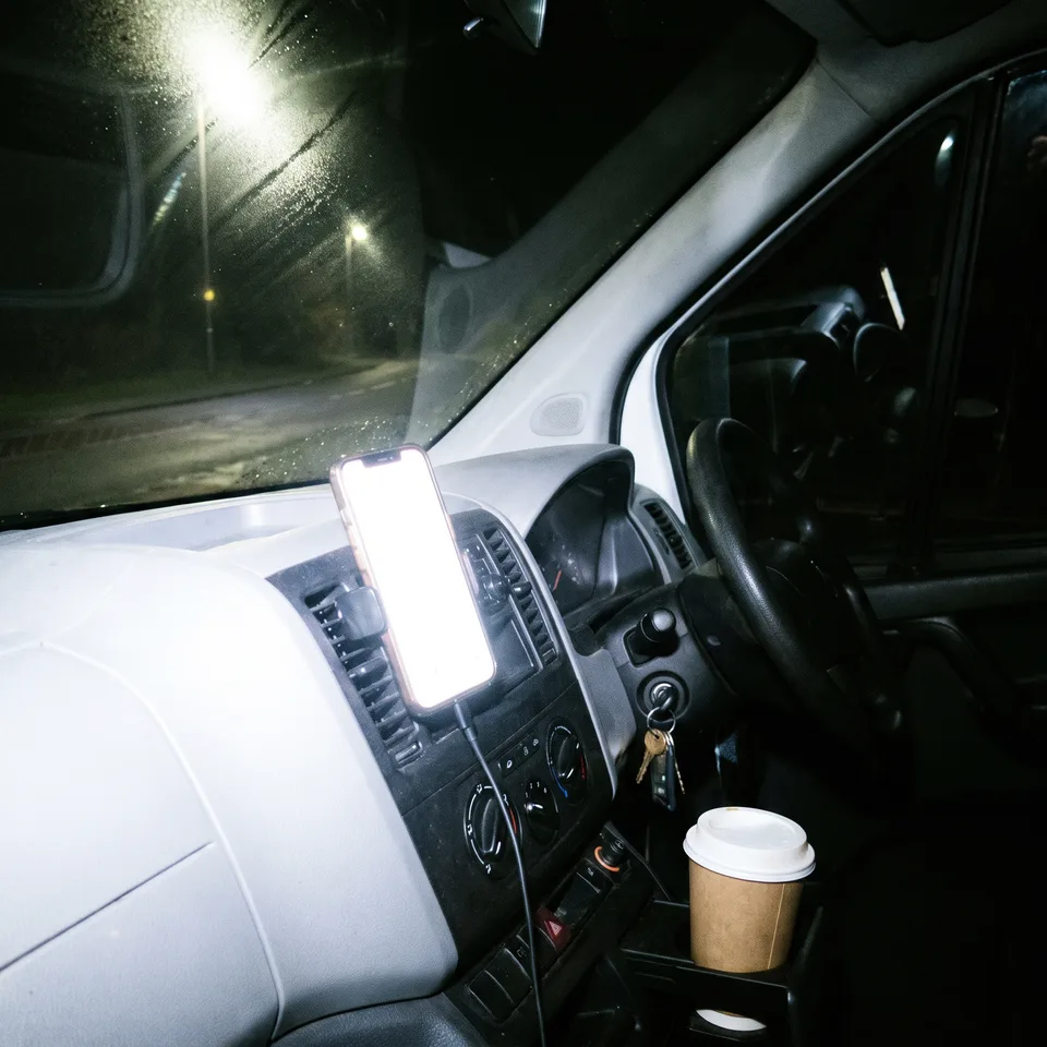 A phone propped against the dashboard inside the van.